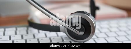 Black headset lying on computer keyboard closeup Stock Photo