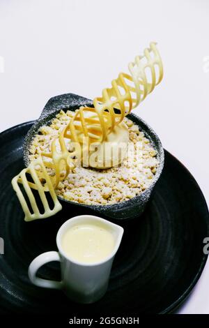 apple crumble with vanilla ice cream and custard sauce in serving dish Stock Photo
