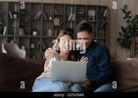 Happy Caucasian couple rest at home using laptop Stock Photo