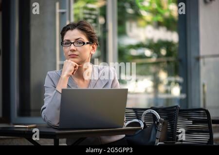 Beautiful business woman is working at a table in an outdoor restaurant. Stock Photo
