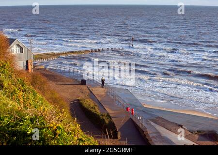 A couple look out to sea next to the lifeboat station at Mundesley on the North Norfolk coast, England. image taken April 2021 Stock Photo