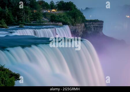 Beautiful Niagara falls close up at night illuminated with colored lights. Long Exposure, American Falls. Cascading waterfalls close up. Stock Photo