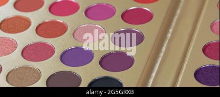 Palette of dry pressed eyeshadows in neutral tones, banner. Round refills of purple, pink, crimson shades. Beauty concept, products for make-up, visag Stock Photo