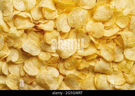 Texture of crispy potato chips. Delicious potato chips with dill background. Popular snack of potatoes deep-fried thin slices. Scattering of chips. Stock Photo