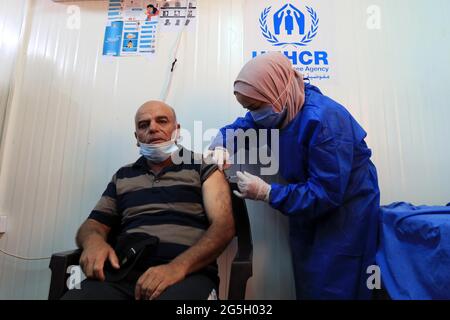 Zaatari, Jordan. 27th June, 2021. A Syrian refugee receives the COVID-19 vaccine at a medical center in the Zaatari refugee camp in Zaatari, Jordan, on June 27, 2021. Out of about 29,000 refugees who are eligible for the COVID-19 vaccine living in Zaatari refugee camp, some 45% of them have received at least their first dose of the vaccine until now, the UN Refugee Agency (UNHCR) Jordan told Xinhua on Sunday. Credit: Mohammad Abu Ghosh/Xinhua/Alamy Live News Stock Photo