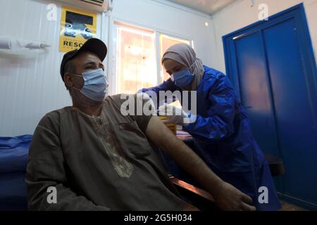 Zaatari, Jordan. 27th June, 2021. A Syrian refugee receives the COVID-19 vaccine at a medical center in the Zaatari refugee camp in Zaatari, Jordan, on June 27, 2021. Out of about 29,000 refugees who are eligible for the COVID-19 vaccine living in Zaatari refugee camp, some 45% of them have received at least their first dose of the vaccine until now, the UN Refugee Agency (UNHCR) Jordan told Xinhua on Sunday. Credit: Mohammad Abu Ghosh/Xinhua/Alamy Live News Stock Photo