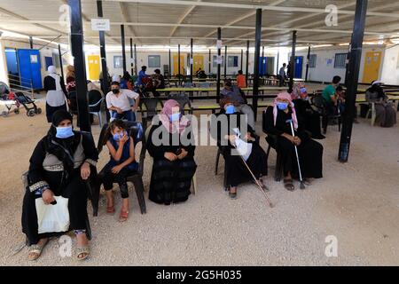 Zaatari, Jordan. 27th June, 2021. Syrian refugees wait to receive the COVID-19 vaccine at a medical center in the Zaatari refugee camp in Zaatari, Jordan, on June 27, 2021. Out of about 29,000 refugees who are eligible for the COVID-19 vaccine living in Zaatari refugee camp, some 45% of them have received at least their first dose of the vaccine until now, the UN Refugee Agency (UNHCR) Jordan told Xinhua on Sunday. Credit: Mohammad Abu Ghosh/Xinhua/Alamy Live News Stock Photo