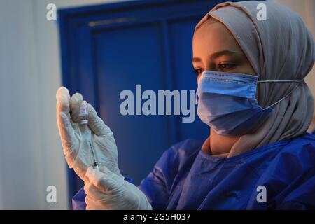 Zaatari, Jordan. 27th June, 2021. A medical worker prepares a dose of the COVID-19 vaccine at a medical center in the Zaatari refugee camp in Zaatari, Jordan, on June 27, 2021. Out of about 29,000 refugees who are eligible for the COVID-19 vaccine living in Zaatari refugee camp, some 45% of them have received at least their first dose of the vaccine until now, the UN Refugee Agency (UNHCR) Jordan told Xinhua on Sunday. Credit: Mohammad Abu Ghosh/Xinhua/Alamy Live News Stock Photo