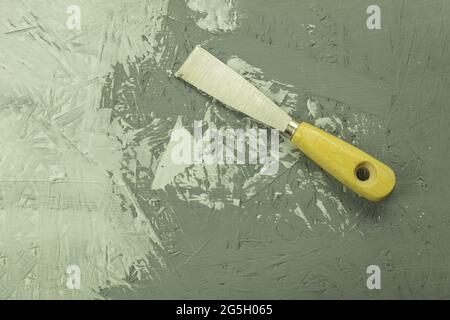 Construction trowel on the table in the process. Renovation process, background with copy space. Putty knife in a putty on the background of the wall Stock Photo