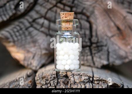 Bottle of homeopathic globules on wooden background. Homeopathy medicine concept. Stock Photo