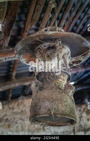 old kerosene lamp hanging from the ceiling of a rural house covered in spiders web Stock Photo