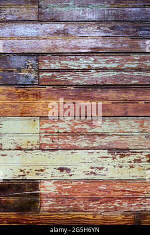 Texture, old grungy paint-striped wood slatted wall covered with peeling paint. Vertical background in brown and green colors. Stock Photo