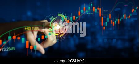 Double exposure of Business man hand on digital stock market financial indicator with night city background. Abstract financial trading graphs. Stock Photo