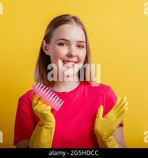 Woman Portrait with cleaning brush in rubber gloves. Young blonde happy smiling woman ready to cleaning house with household supplies isolated over Stock Photo