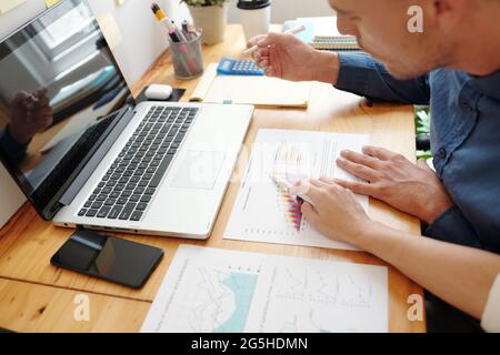 Hands of entrepreneurs having meeting in office to discuss ascending chart in sales data report Stock Photo