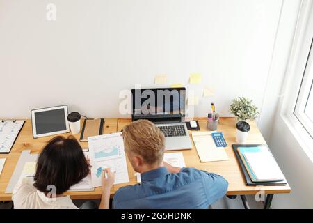 Business people sitting at office desk and anzlyzing charts and diagrams in sales report, view from above Stock Photo
