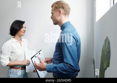 Smiling young businesswoman looking at coworker explaining his creative idea Stock Photo
