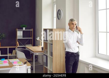 Senior businessman is busy talking on a mobile phone solving various problems at work. Stock Photo
