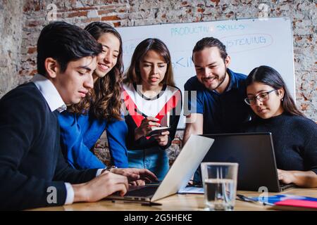 Group of young latin business people working with computer while spending time in the office in Mexico Stock Photo