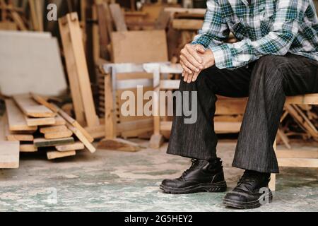 Cropped image of elderly carpenter resting after working with wood in his workshop Stock Photo