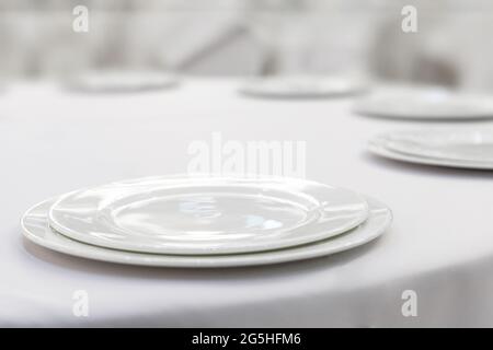 Empty white plates on a white tablecloth. Restaurant setting. Stock Photo