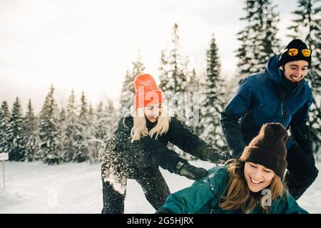Happy male and female friends playing at ski resort during winter Stock Photo