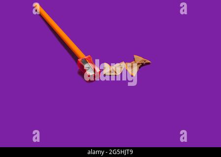 pencil and a sharpener with shavings on purple layout Stock Photo