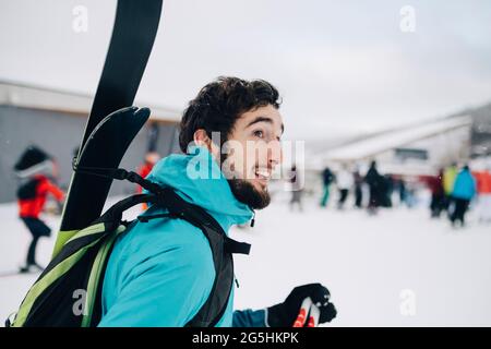 Bearded man wearing backpack while looking away at ski resort Stock Photo