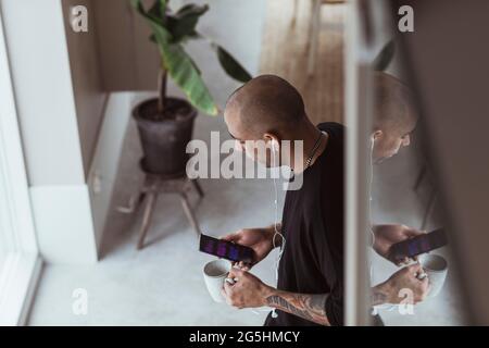 High angle view of man using smart phone while standing at home Stock Photo