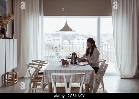 Businesswoman working at dining table in living room Stock Photo