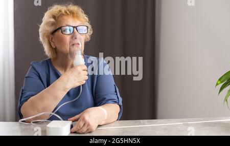 Elderly woman using asthma machine at home Stock Photo
