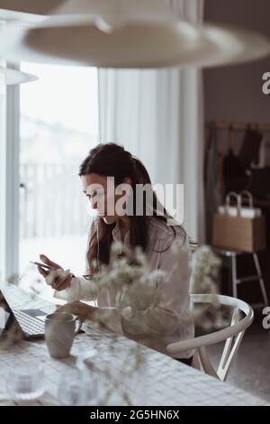 Businesswoman working on laptop at table from home Stock Photo
