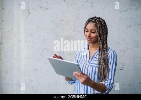 Portrait of young woman freelancer standing indoors, using tablet. Stock Photo