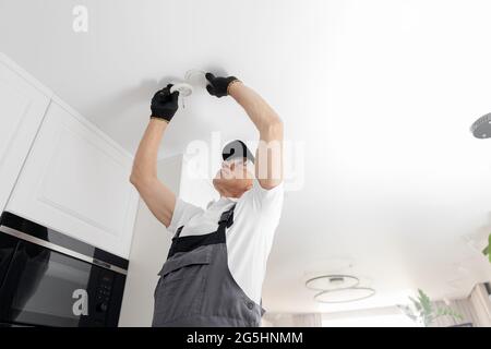 Electrician worker install replaces LED lighting lamp in apartment. Stock Photo