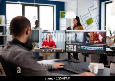 Videographer in web online conference with project manager on video call editing client work, getting feedback on commercial movie using post production software on two monitors in start up office Stock Photo