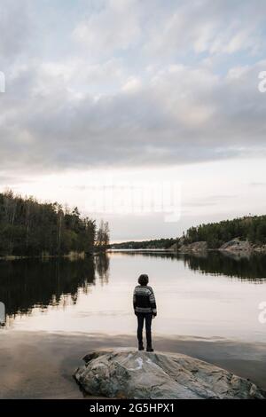 Rear view of female explorer looking at view while standing on rock Stock Photo