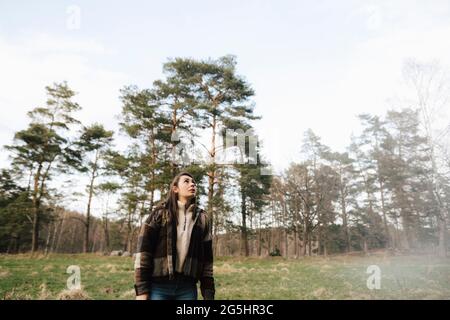 Female hiker looking up while exploring in forest Stock Photo
