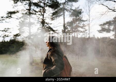 Young female hiker exploring forest during foggy weather Stock Photo