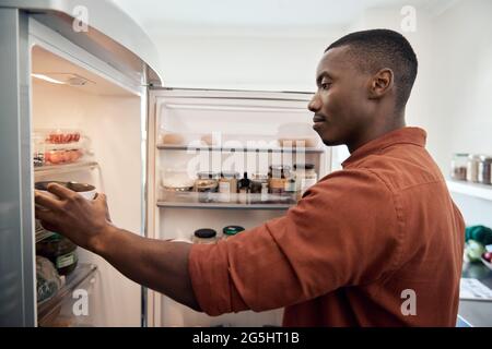 Young African man looking for something in his refrigerator Stock Photo