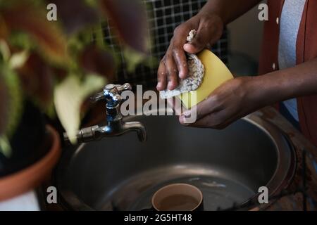 African man washing some dishes in his kitchen sink Stock Photo