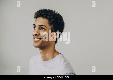 Smiling young man with curly hair against white background Stock Photo