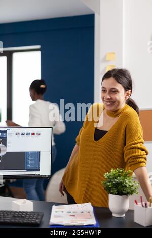 Industrial architect colleagues working and having fun sharing ideas for new mechanical project. Engineers using pc with CAD software and two monitors in start up company innovating motor prototype. Stock Photo