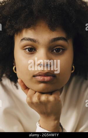 Portrait of curly haired woman with hand on chin Stock Photo