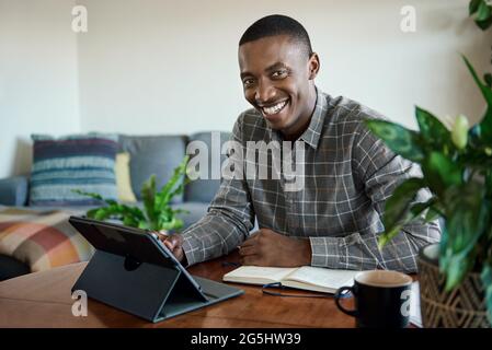 Smiling young African businessman working on a tablet at home Stock Photo
