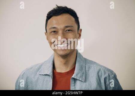 Portrait of smiling man wearing blue jacket against beige background Stock Photo