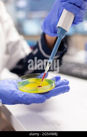 Close up of doctor dropping blood sample using micropipette in medicine lab. Medical stuff examining vaccine evolution using high tech and technology researching treatment, development. Stock Photo