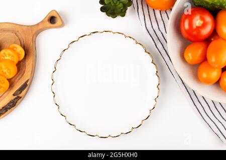 Dinner plate mockup. White plate in the kitchen with tomatoes on a white table. Flat lay mock up Stock Photo