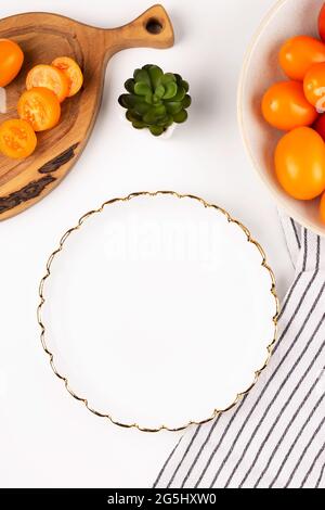 Dinner plate mockup. White plate in the kitchen with tomatoes on a white table. Flat lay mock up Stock Photo