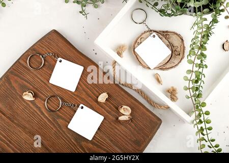 Keychain mockup among olive leaves to display design. Blank white sublimation  key chain photo. Stock Photo