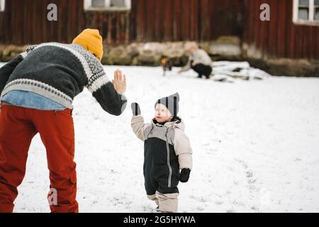 Rear view of mother giving high-five to daughter during winter Stock Photo